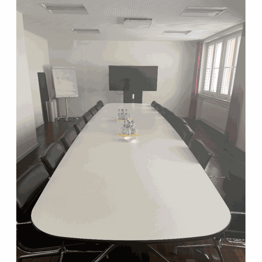 Moderner Vitra Segmented Tisch 560x136cm im Besprechungsraum mit schwarzen Stühlen und großem Bildschirm