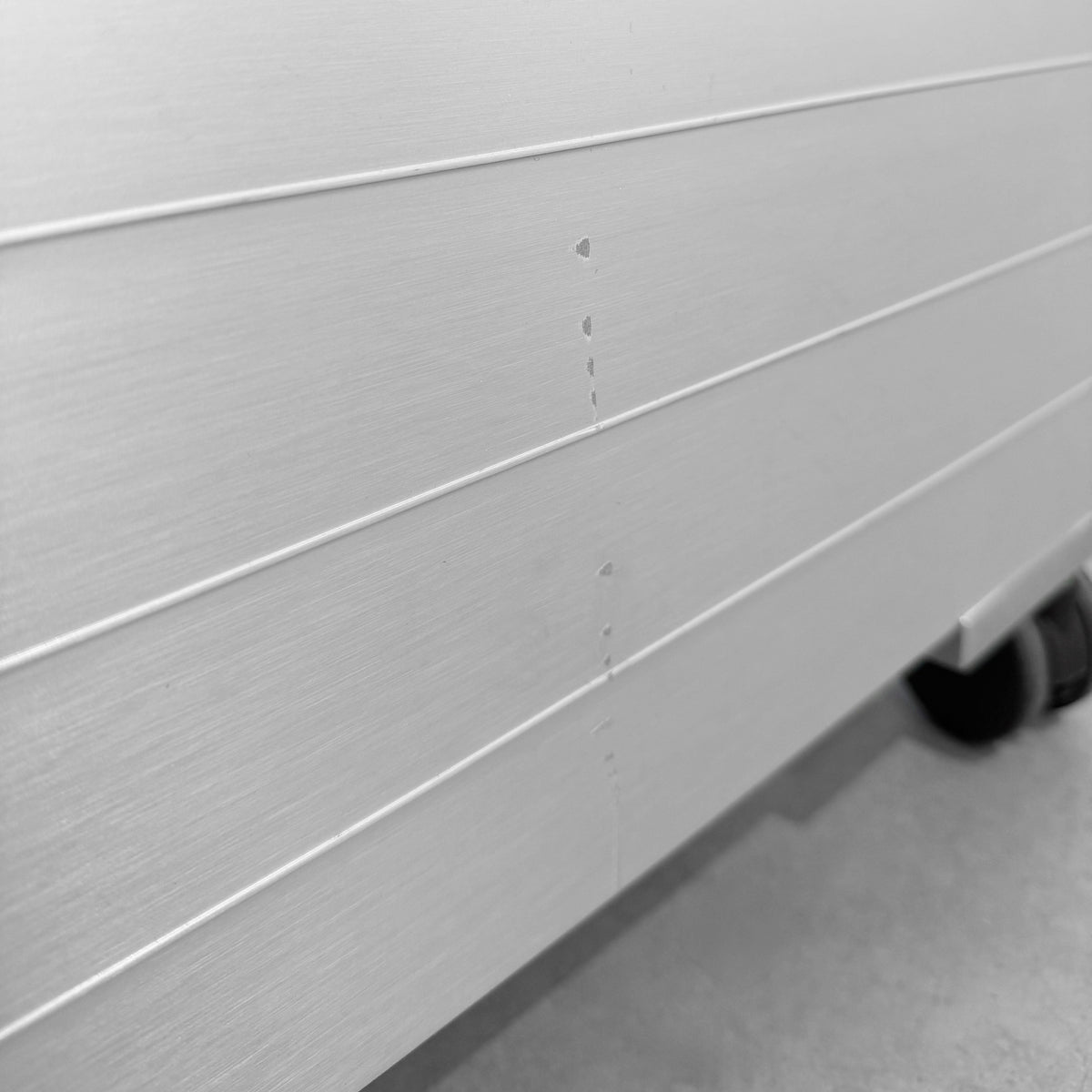 Detailansicht der Aluminium-Rückseite des Vitra Spatio Rollcontainers mit kleiner Schramme.
