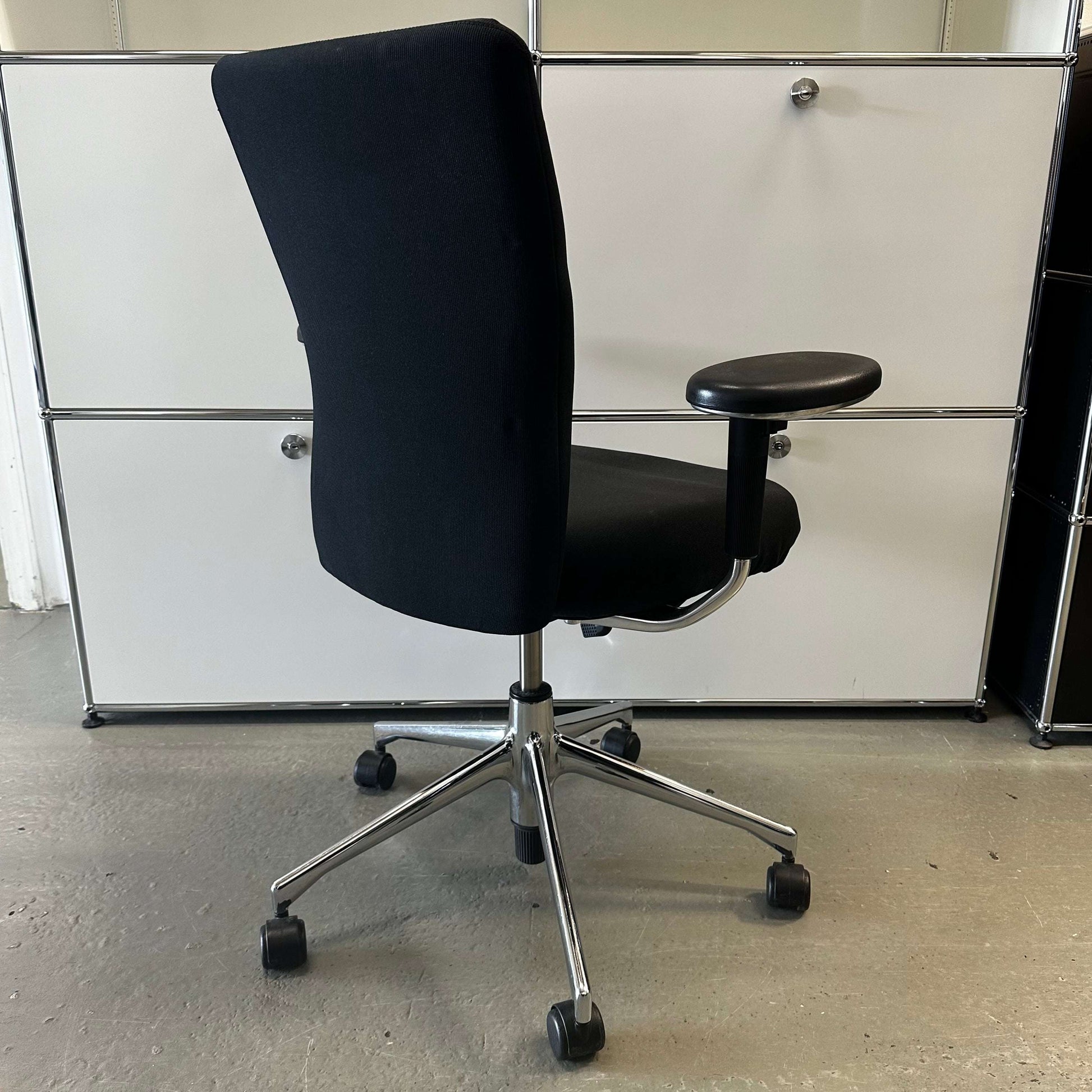 Black Vitra T-Chair with adjustable armrest and chrome base on wheels in modern office setting