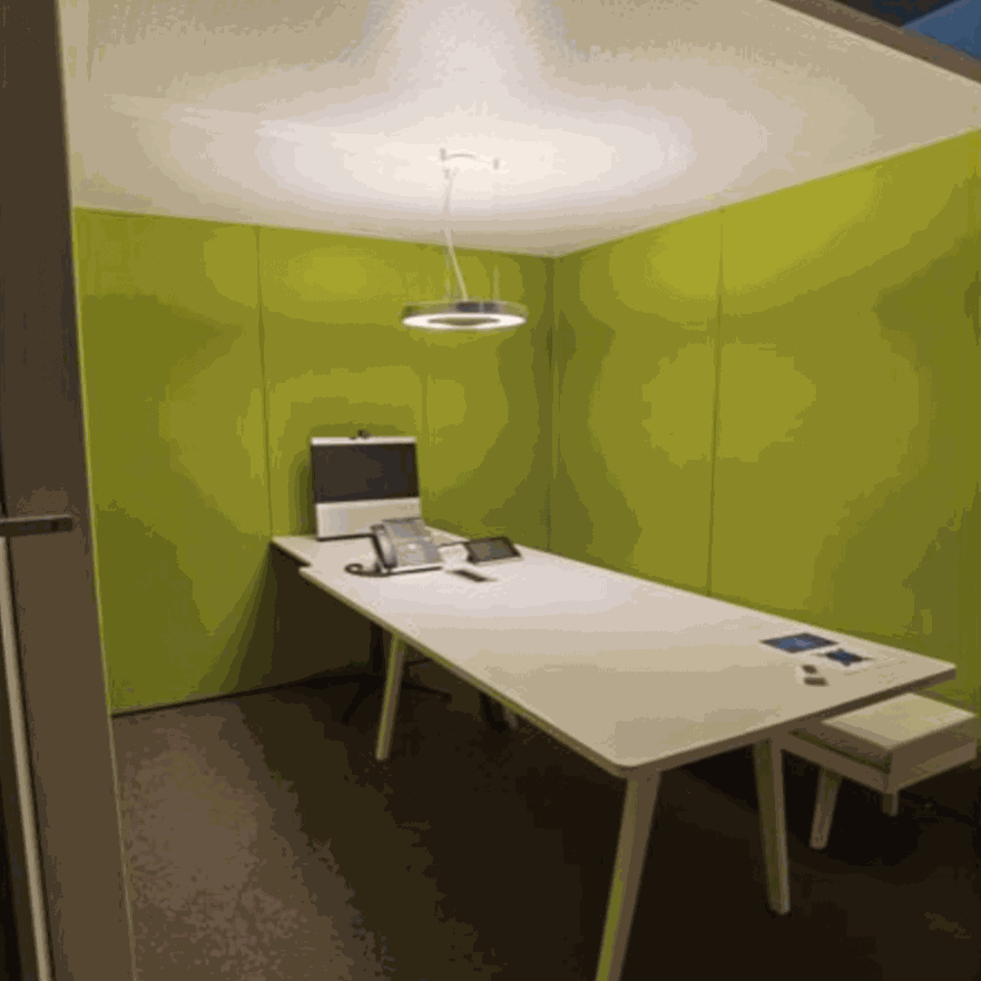 Vitra ThinkTank SilentWall team workspace with green fabric and perforated metal walls, white table, modern ceiling lamp, designed by Arik Levy.