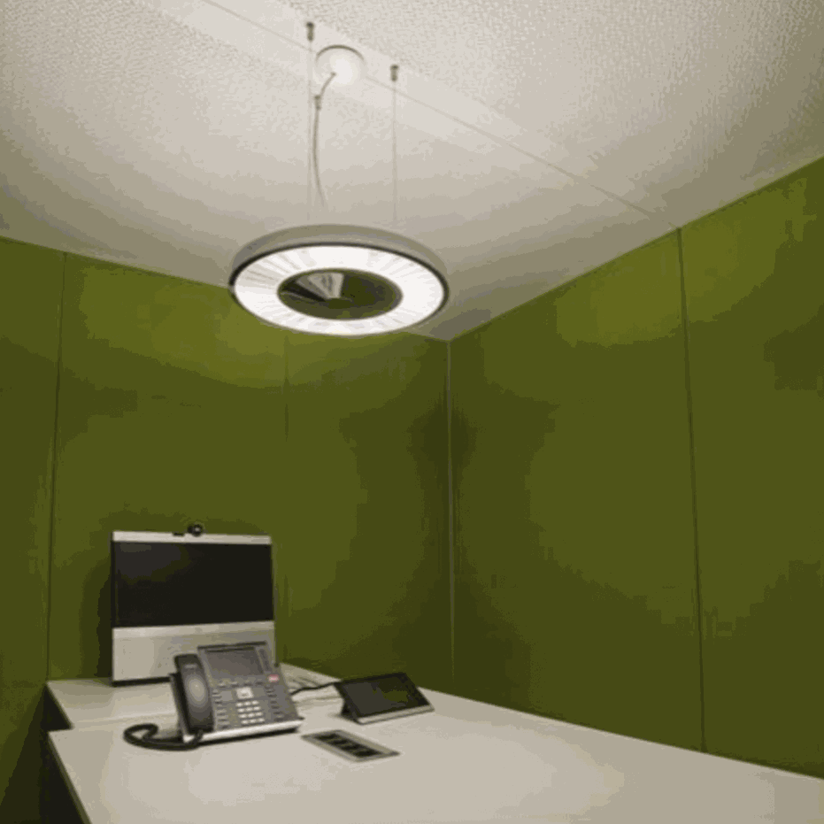 Vitra ThinkTank SilentWall team workspace with green fabric walls, white table, office phone, computer, and circular ceiling light