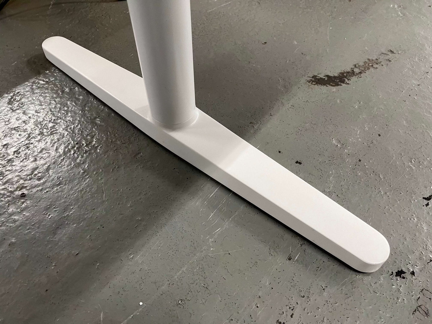 White soft light powder-coated base of Vitra Tyde Konferenztisch on gray floor