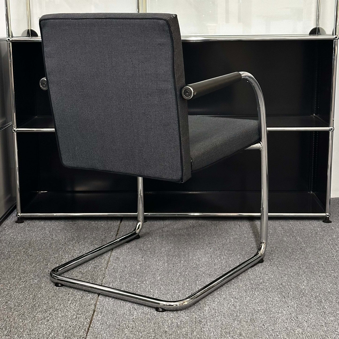 Black and grey Vitra Visasoft cantilever visitor chair with chrome frame and fabric upholstery in modern office setting