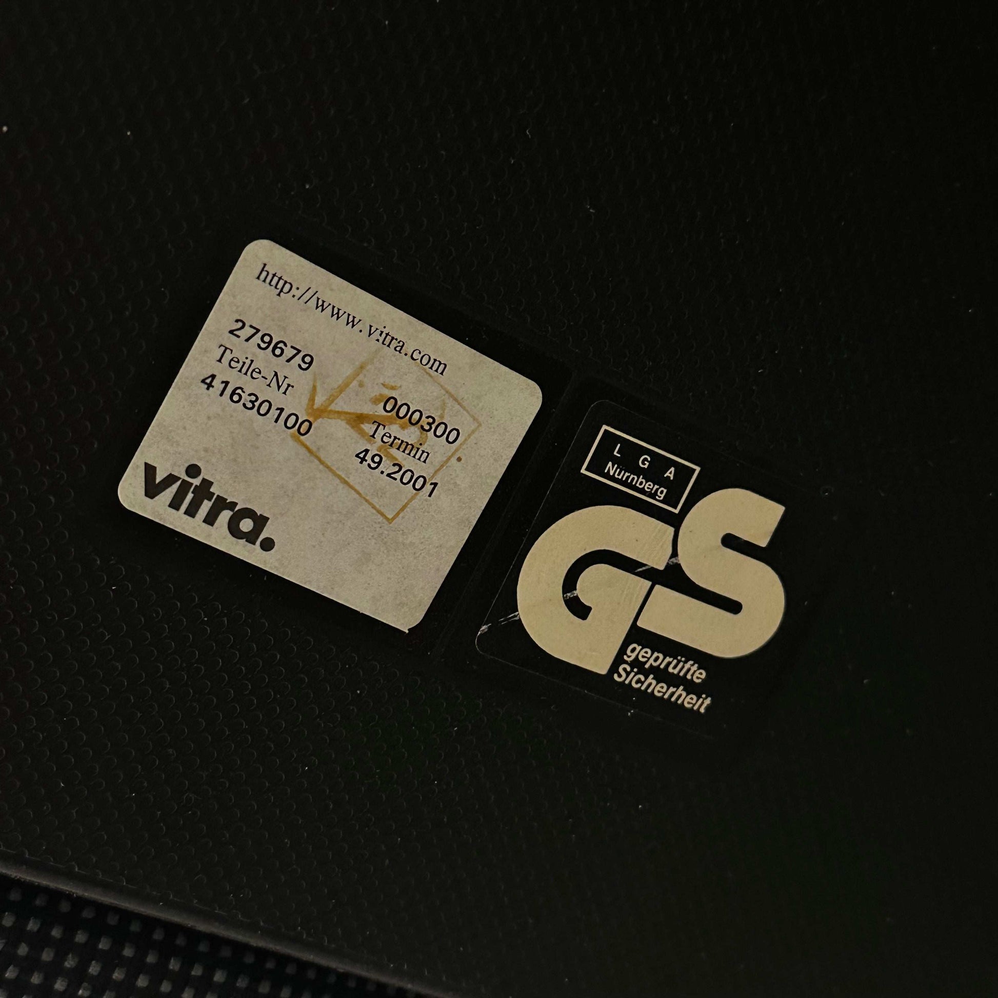 Close-up of Vitra Visasoft visitor chair label on black and gray fabric upholstery