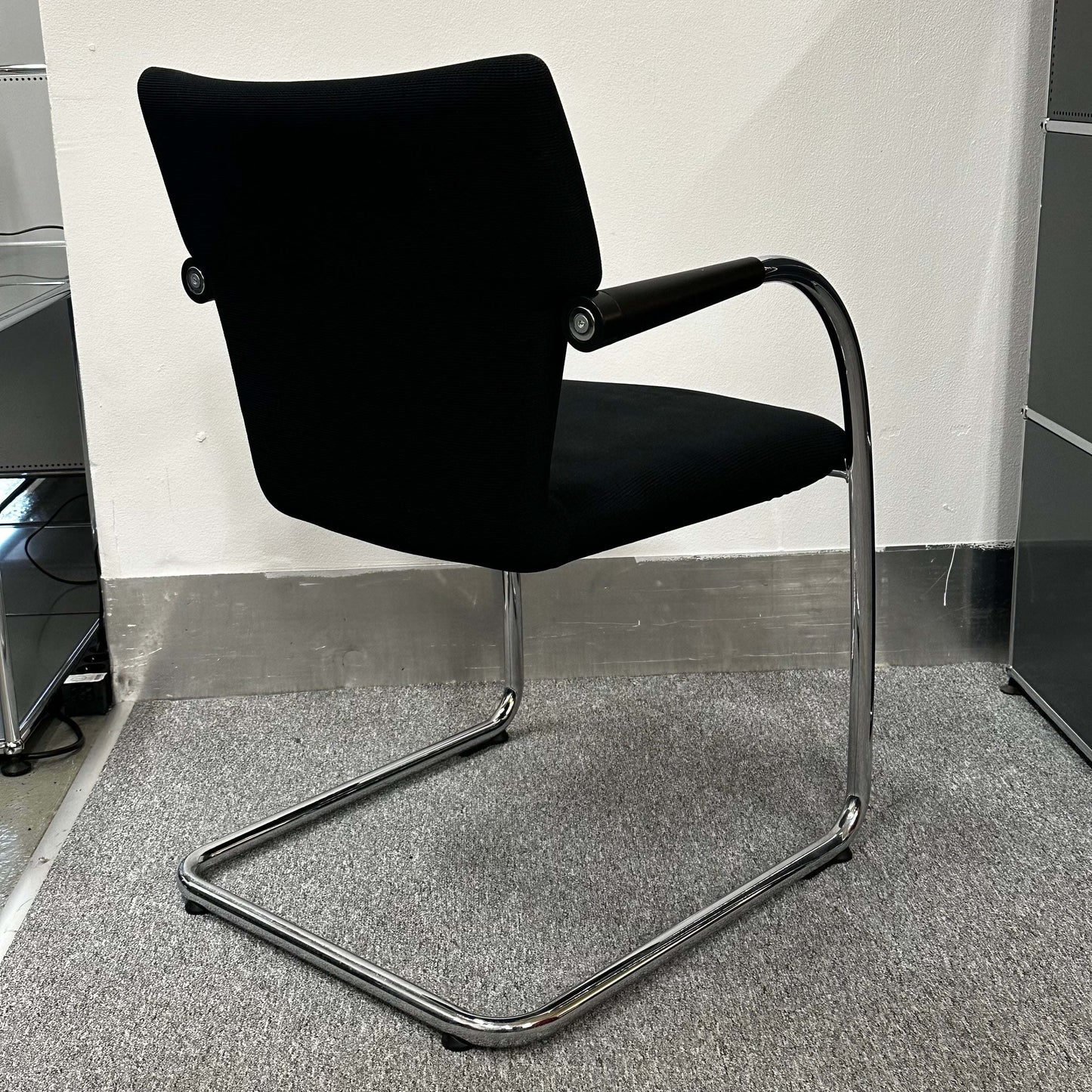 Black Vitra Visastripe conference chair with chrome cantilever frame and armrests on gray carpet
