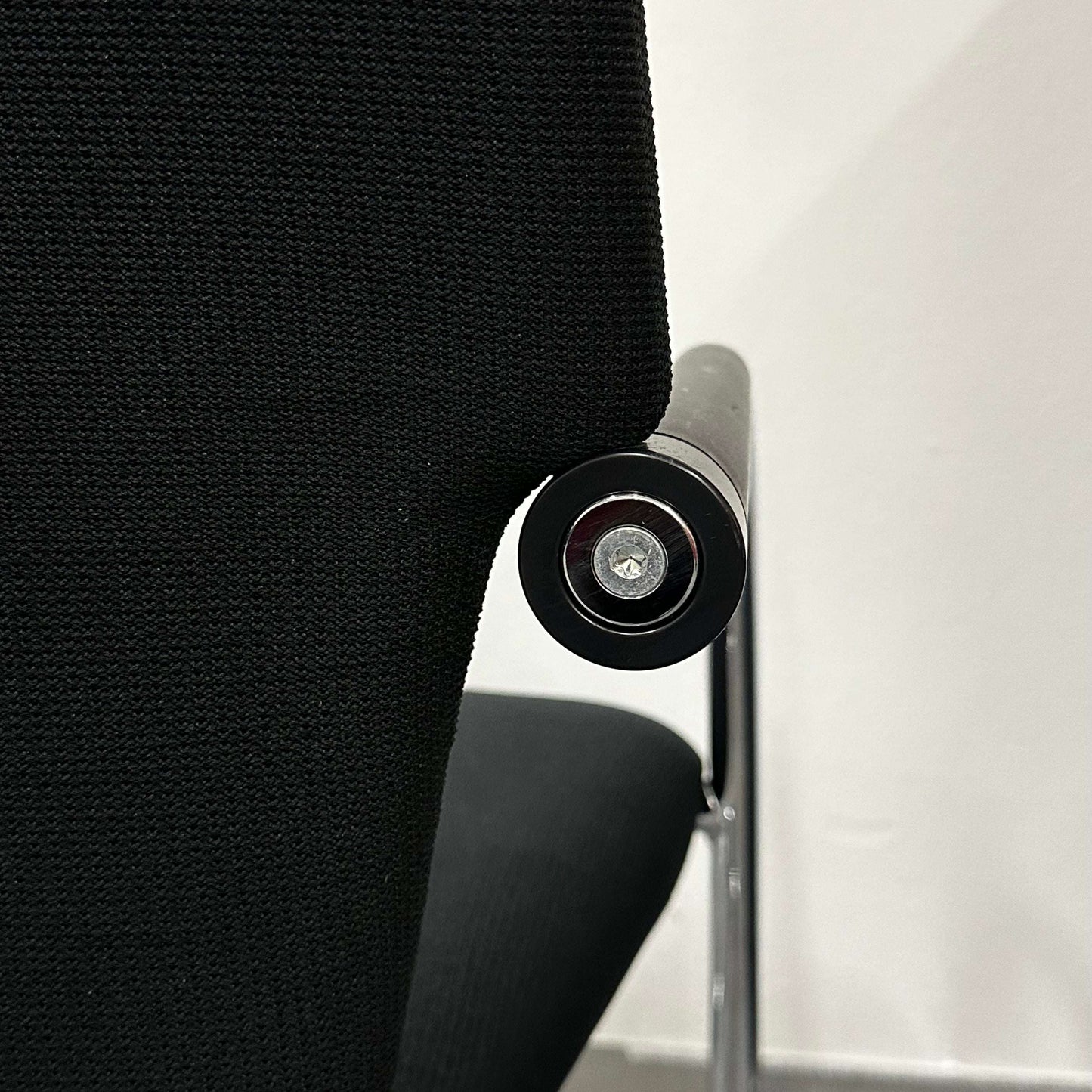 Close-up of black Vitra Visastripe conference chair with modern ergonomic design and metallic armrest detail