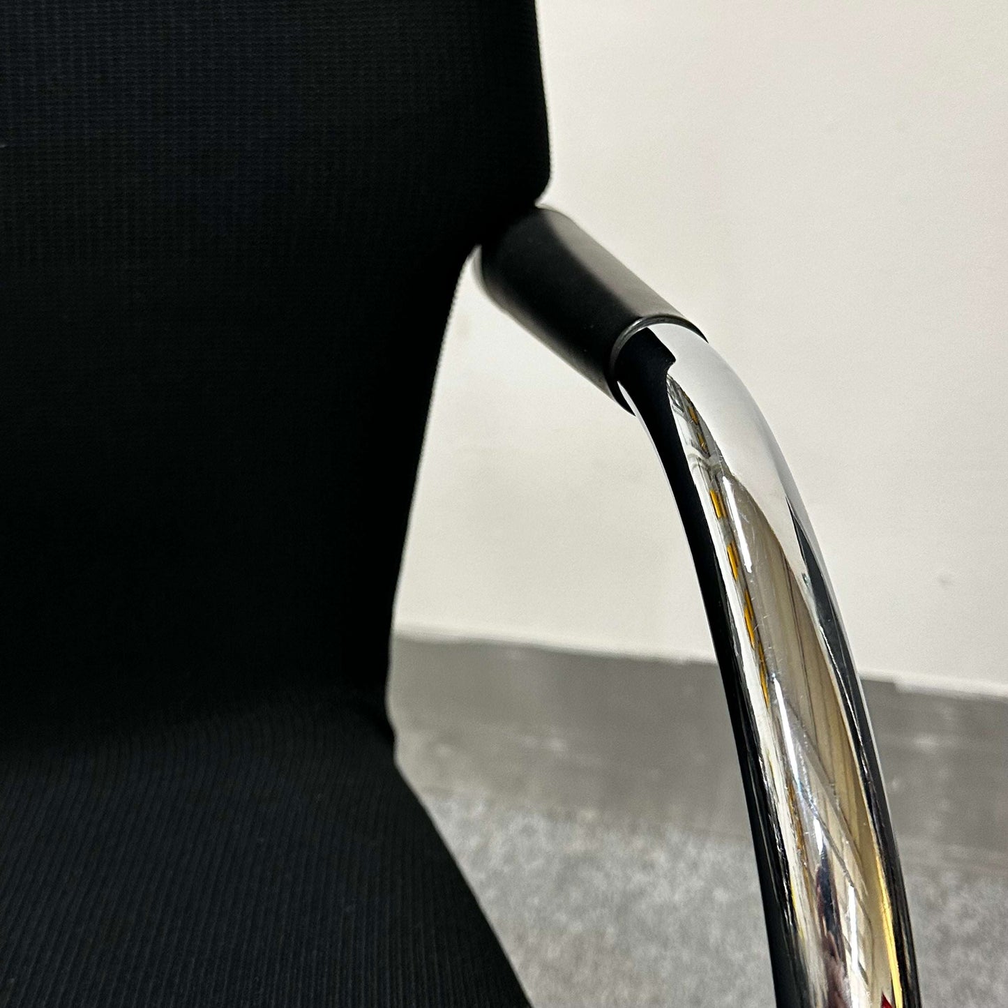 Close-up of Vitra Visastripe conference chair showing black fabric seat and chrome armrest