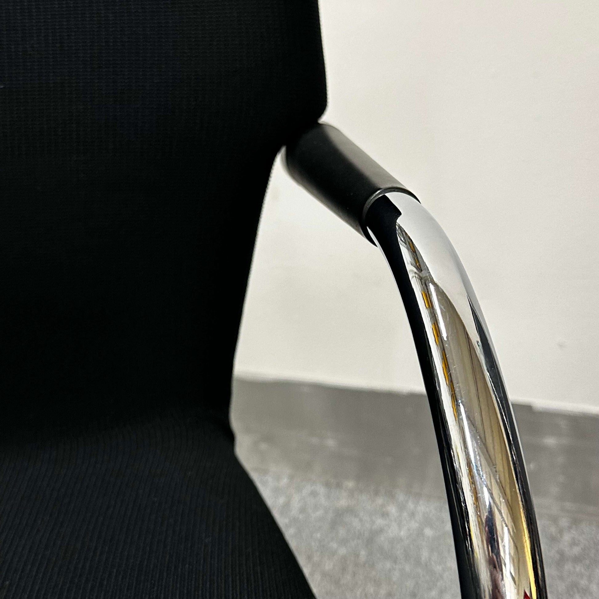 Close-up of Vitra Visastripe conference chair showing black fabric seat and chrome armrest