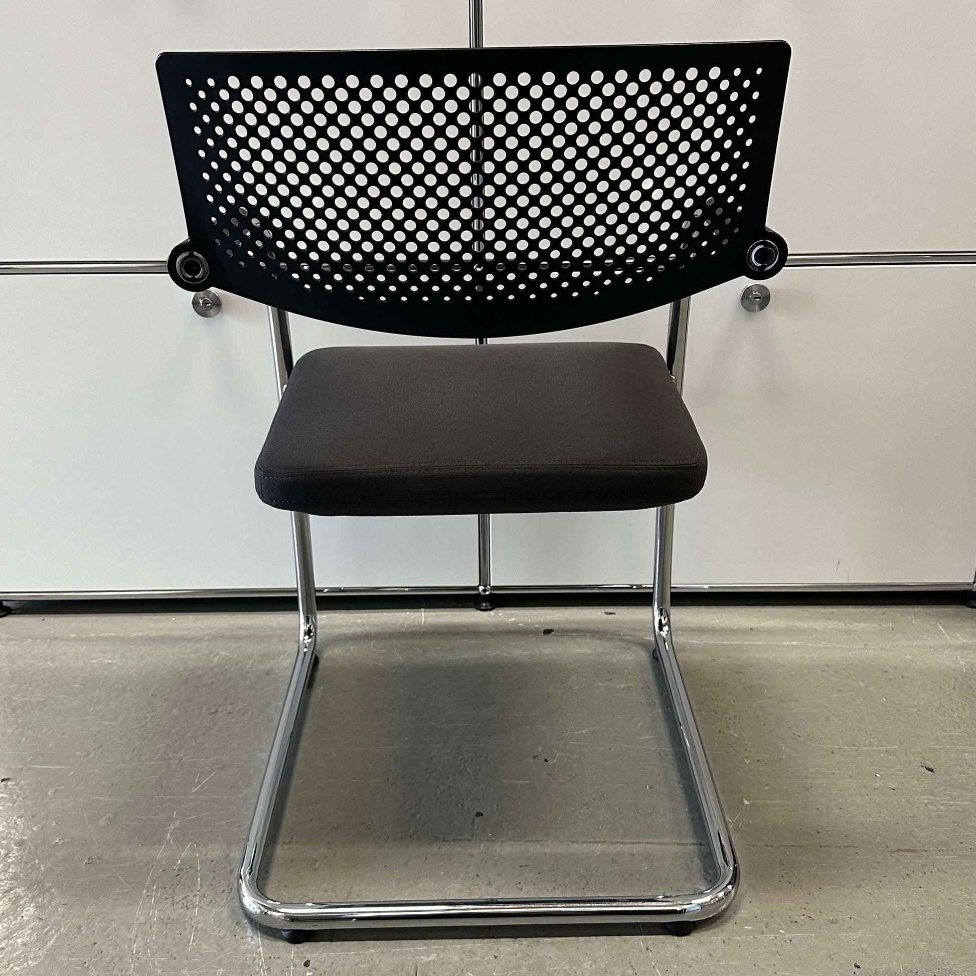 Vitra Visavis 2 chair with dark grey fabric seat, black perforated plastic backrest, and chrome frame.
