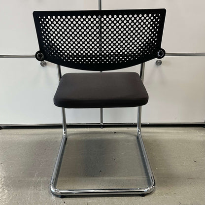 Vitra Visavis 2 chair with dark grey fabric seat, black perforated plastic backrest, and chrome frame.