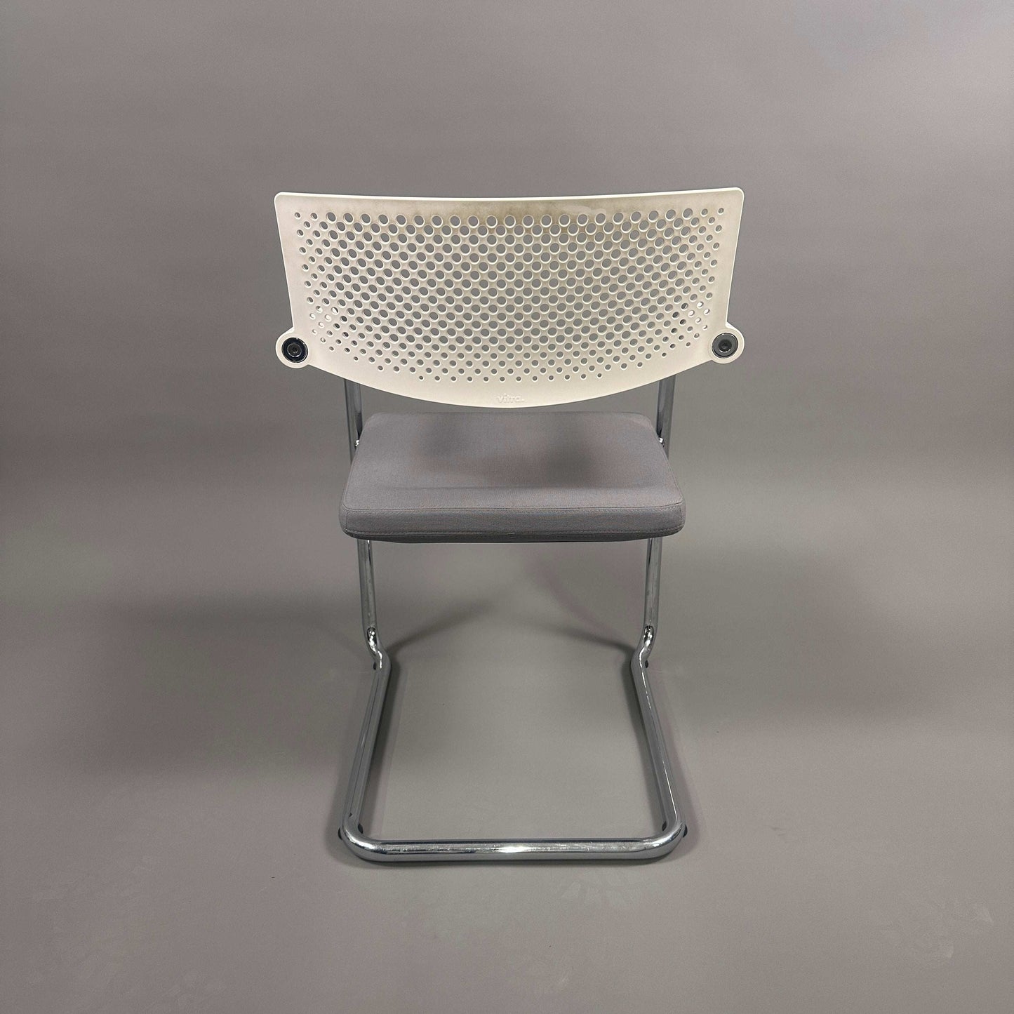 Vitra Visavis 2 chair with gray padded seat, white perforated plastic backrest, and chrome frame, stackable design.