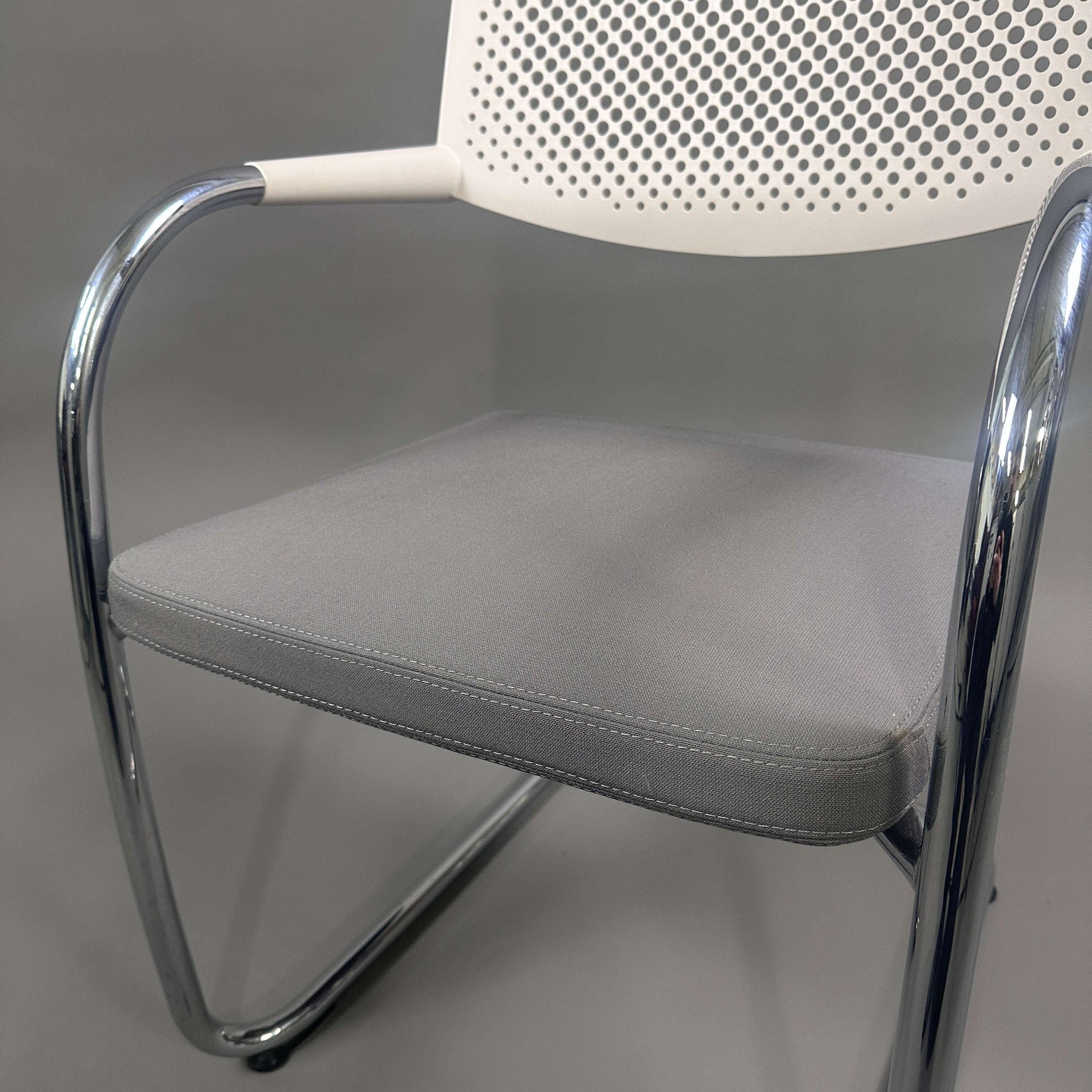 Vitra Visavis 2 chair with grey padded seat, white perforated plastic backrest, and chrome frame