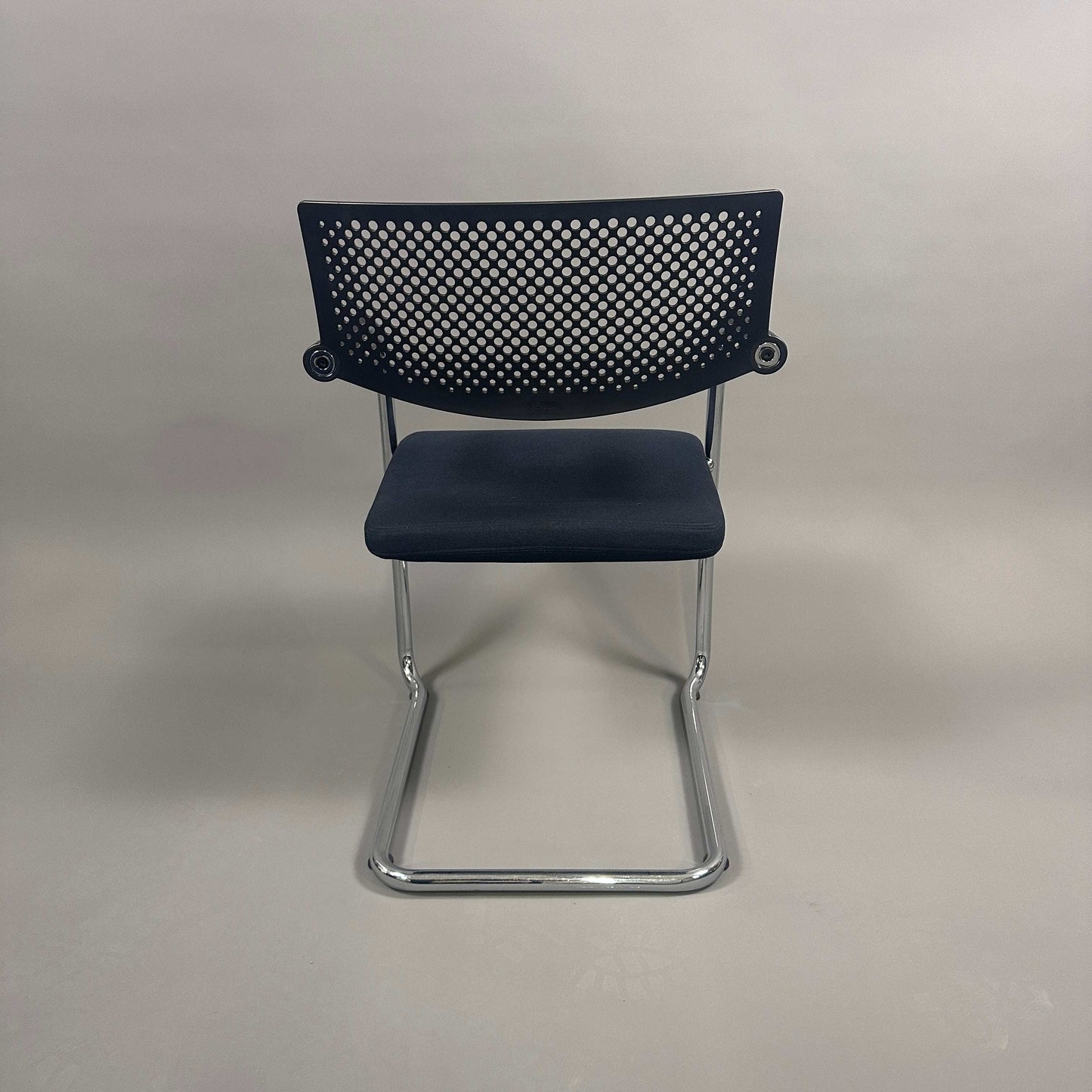 Vitra Visavis 2 black visitor chair with black fabric seat, perforated black plastic backrest, and chrome frame