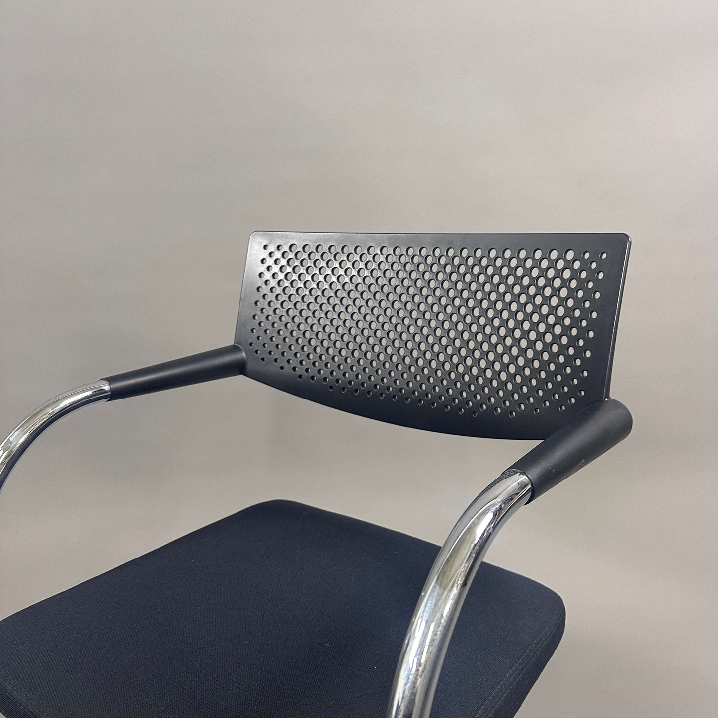 Vitra Visavis 2 black visitor chair with perforated backrest, black fabric seat, and chrome frame