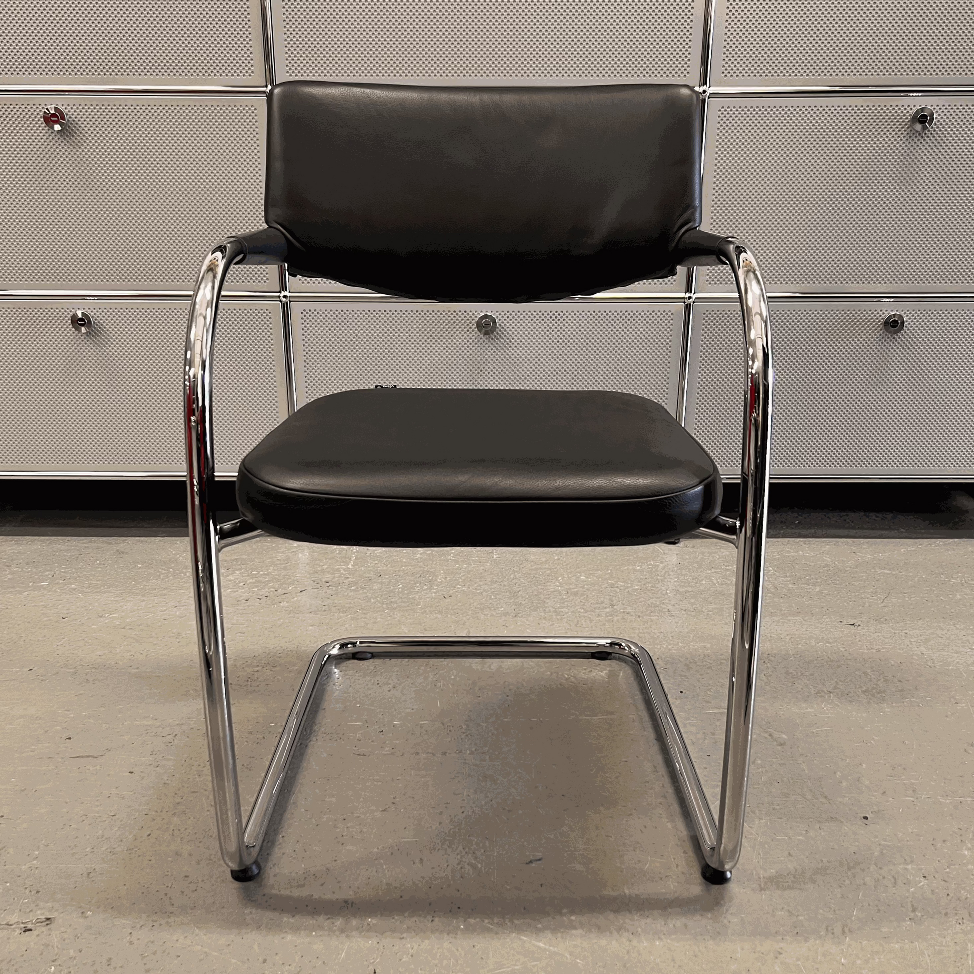 Vitra Visavis chair with black softback leather and chrome frame in modern office setting