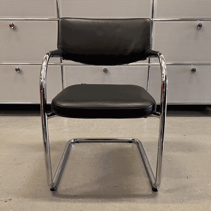 Vitra Visavis chair with black softback leather and chrome frame in modern office setting