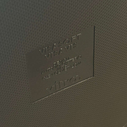 Close-up of embossed Vitra Visavis Softback logo on dark blue textured surface of chair backrest with padded upholstery.