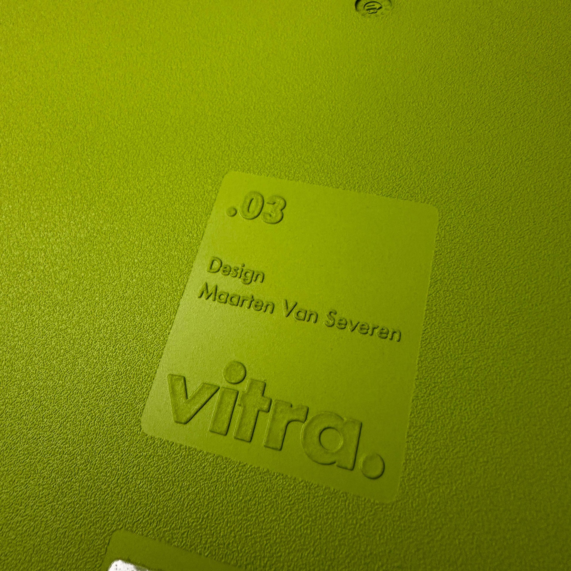 Close-up of Vitra .03 Besucherstuhl avocado chair label with textured plastic surface and embossed designer name Maarten Van Severen.
