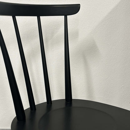 Close-up of the black Wagner W-1960 Chairity with slim vertical backrest slats against a plain wall.