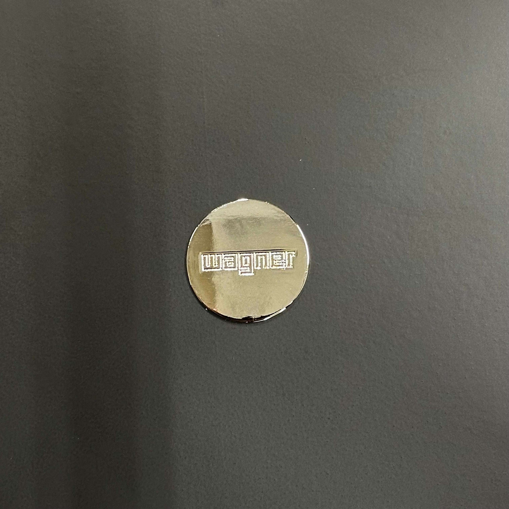 Wagner W-1960 Chairity metal logo badge on dark chair surface