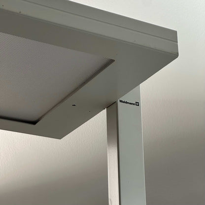 Close-up of white Waldmann Lavigo LED floor lamp with integrated motion and daylight sensor.