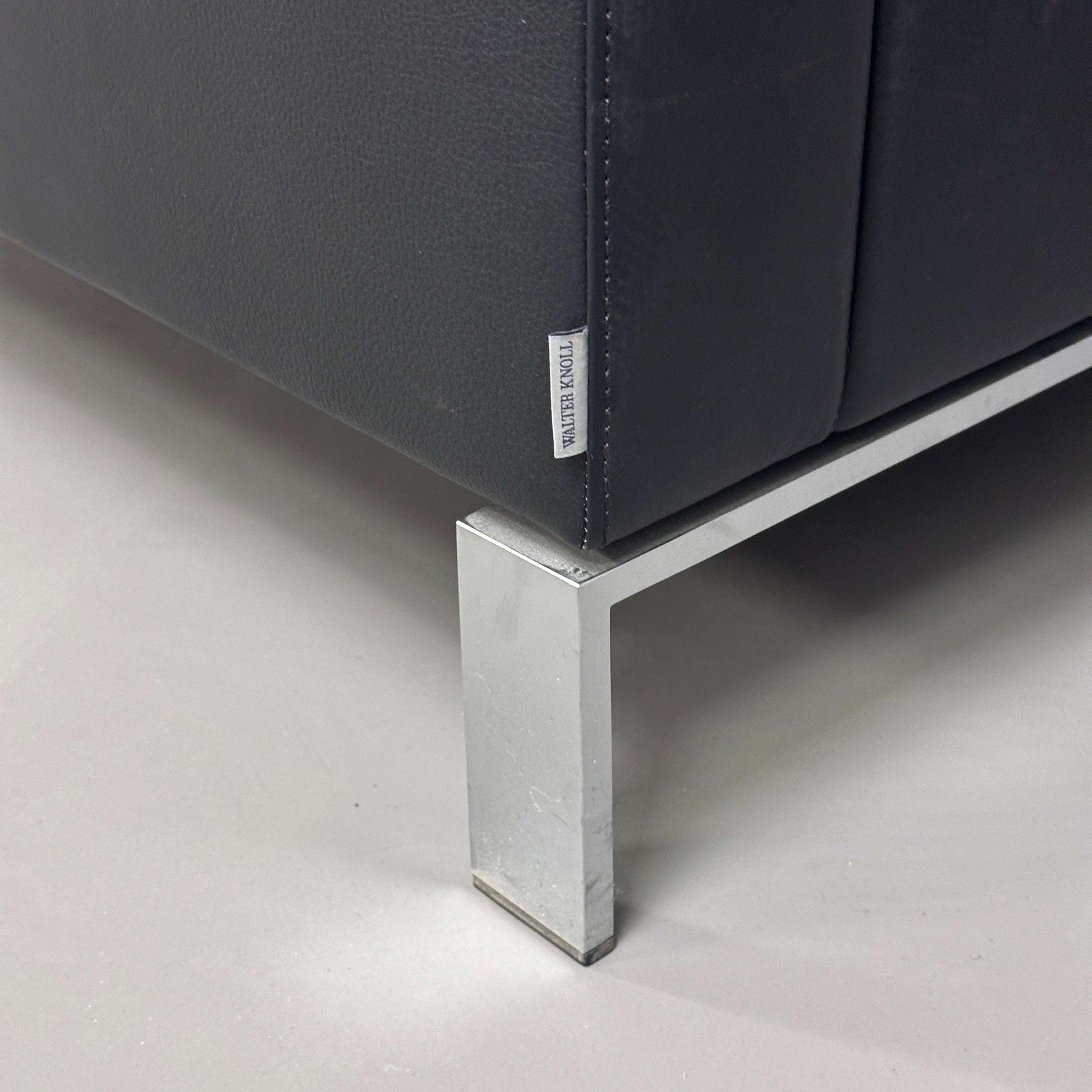 Close-up of black Walter Knoll Foster 500 leather armchair corner with chrome-plated spring steel frame leg and visible Walter Knoll label