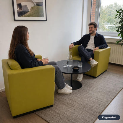 Zwei Personen sitzen in modernen, grün-gelben Walter Knoll Ledersesseln mit kubischem Design an einem runden schwarzen Tisch.