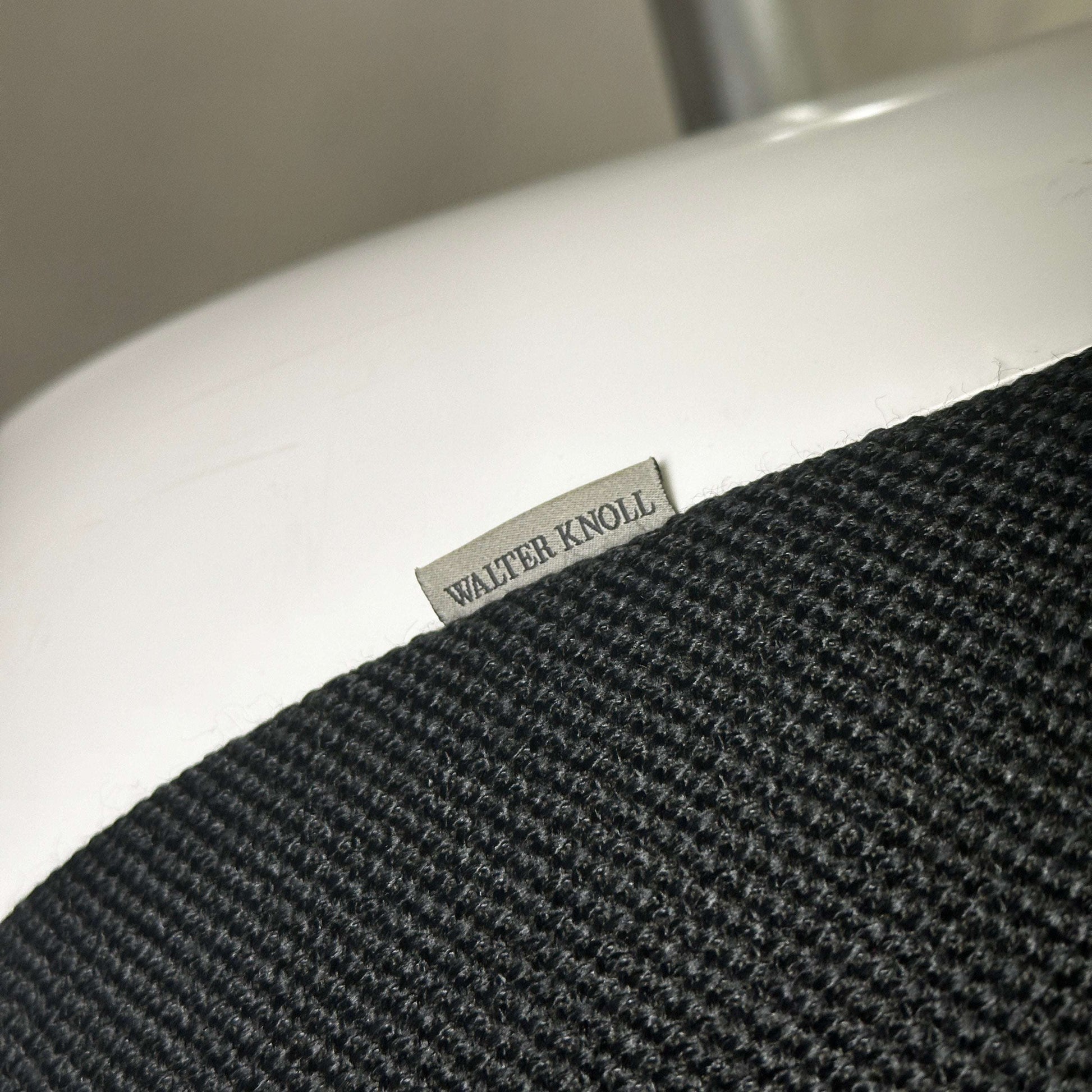 Nahaufnahme des Walter Knoll Turtle Lounge Chair mit schwarzem Stoffbezug und weißem Aluminium-Rundfußgestell