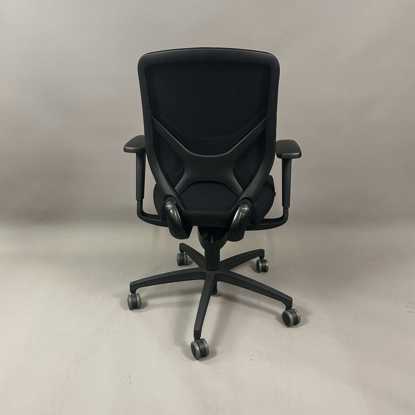 Wilkhahn IN ergonomic black office chair with mesh back, adjustable armrests, and soft casters for hard floors.