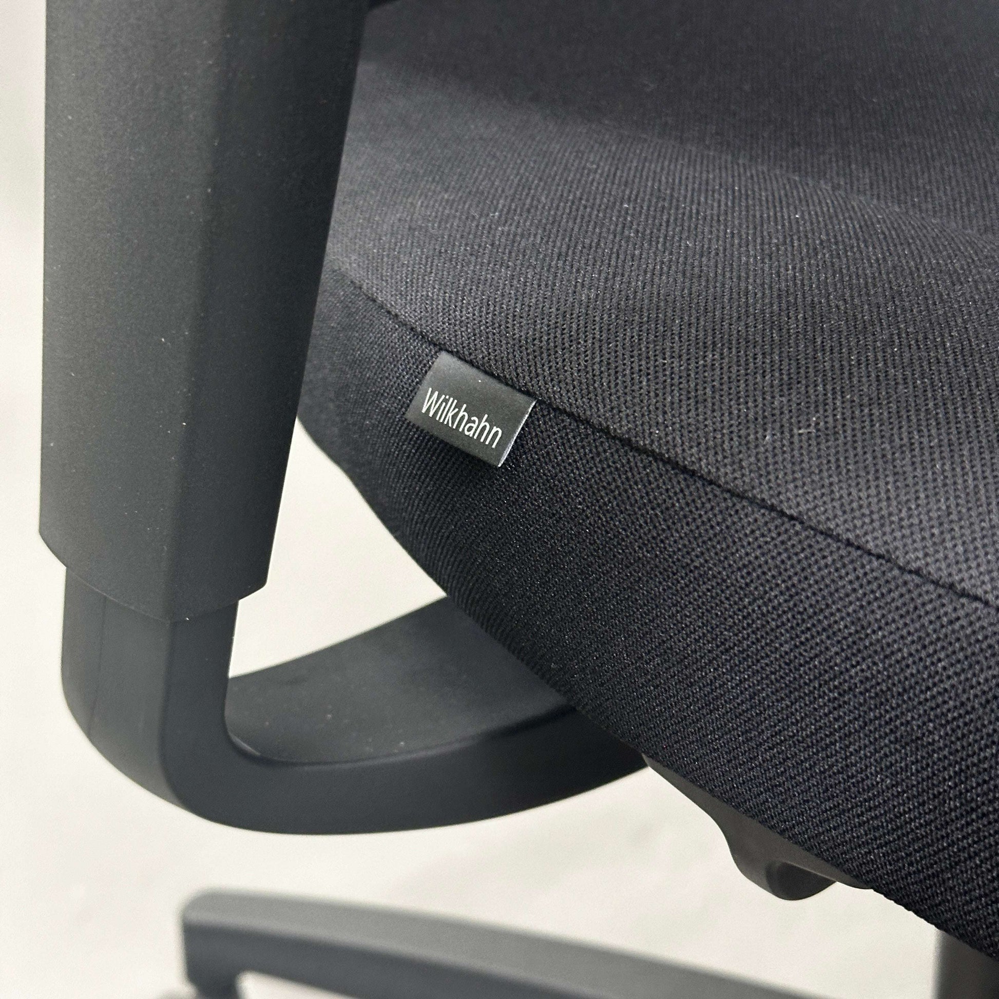 Close-up of Wilkhahn IN office chair seat with black fabric and plastic armrest