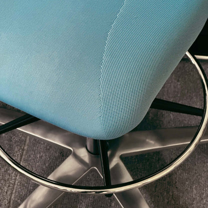 Close-up of blue Wilkhahn In 284/1 Counterstuhl ergonomic swivel counter chair with metal footrest ring and base