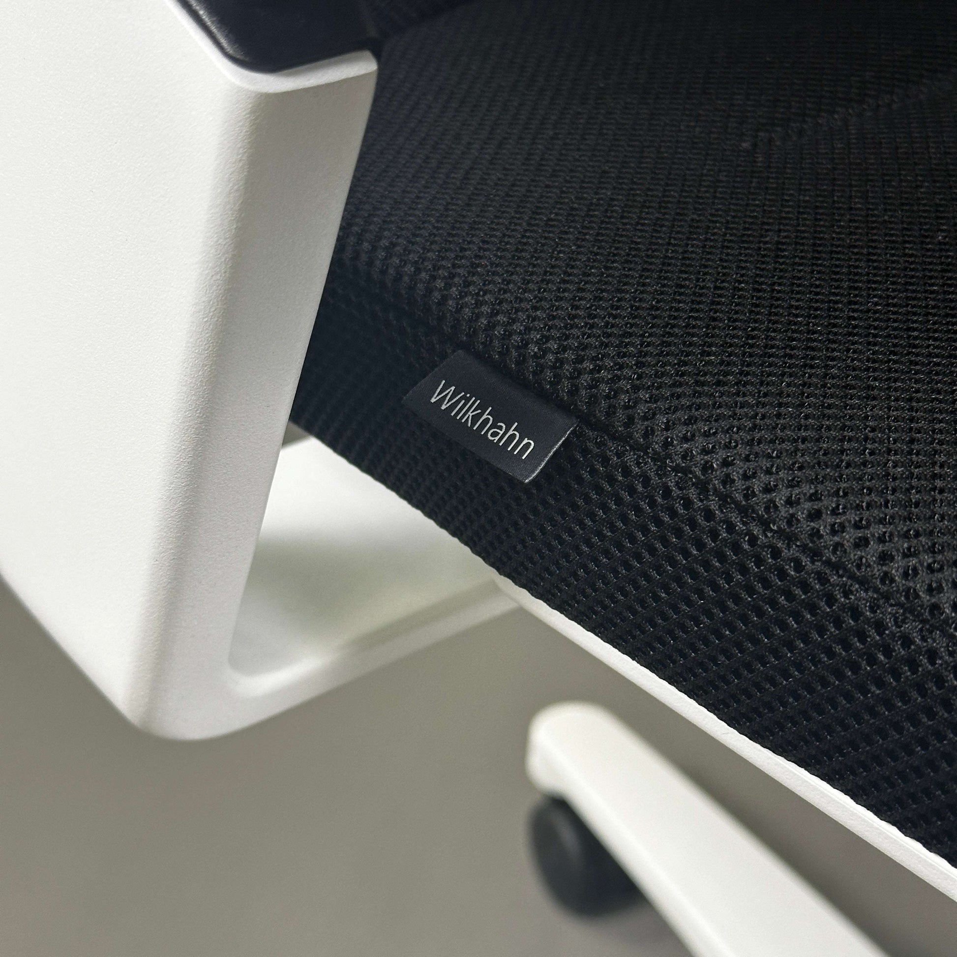 Close-up of Wilkhahn ON office chair seat with black Fiberflex fabric and white plastic frame