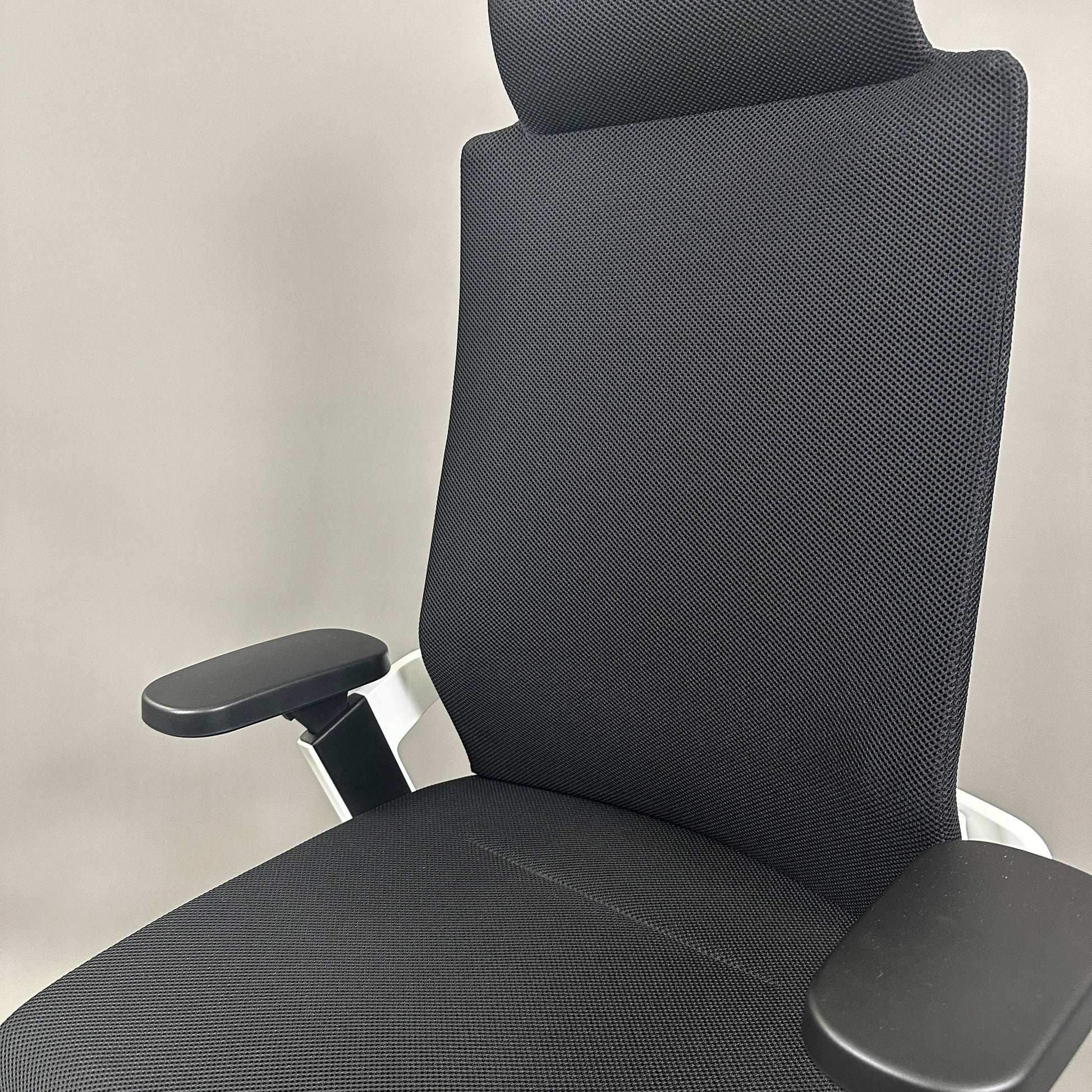 Wilkhahn ON ergonomic office chair with high backrest, black Fiberflex upholstery, white plastic base, 3D adjustable armrests, and universal casters